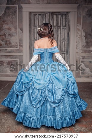 Beautiful medieval woman in long blue dress, back  Royalty-Free Stock Photo #217578937