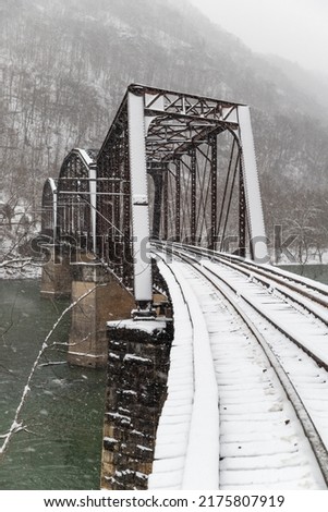 Antique and Rusty Railroad Bridge for Chesapeake and Ohio Railroad and CSX - Skewed Pratt Through Truss - Snowy Winter Scene - New River Gorge National Park and Preserve - Fayetteville, West Virginia Royalty-Free Stock Photo #2175807919