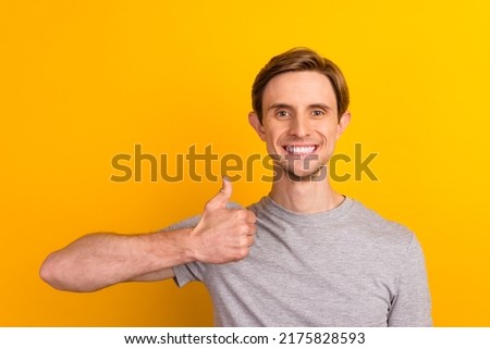 Young handsome man isolated over bright background approving doing positive gesture with hand thumbs up for success