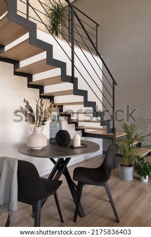 Small, round dining table with two chairs under wooden stairs