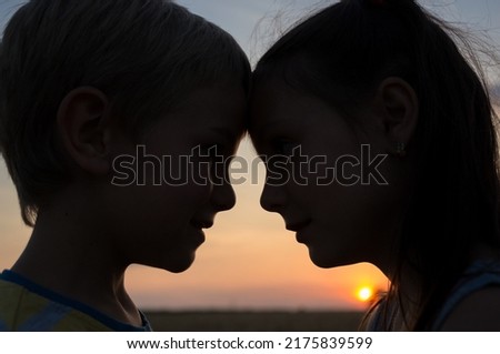 close-up silhouettes of the heads of a boy and a girl, pressing their foreheads against each other against the backdrop of setting sun. tender feelings, pleasant pastime, friendship. Valentine's Day