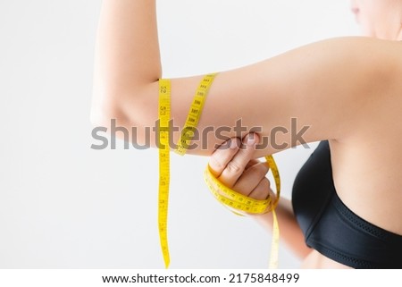 Close-up of a woman grabbing upper arm with excess fat. Pinching the loose and saggy muscles. Woman diet lifestyle concept. Royalty-Free Stock Photo #2175848499
