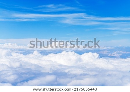 Aerial view of the fluffy cloud on blue sky. High in the Heavens. White Clouds from above.  Top view from an airplane over white clouds in a blue sky.  Royalty-Free Stock Photo #2175855443