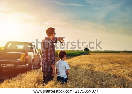 father and son outdoor on wheat field. farmers life concept. father showing their land to his son Royalty-Free Stock Photo #2175859077