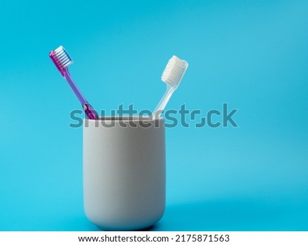 Toothbrushes in a glass with copy space on a blue background.
