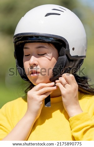 Woman fastening the safety helmet to drive a motorcycle
