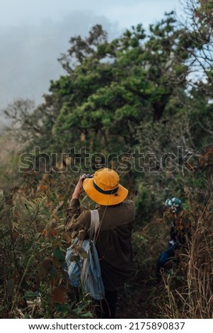 A hiker taking a picture with a yellow hat