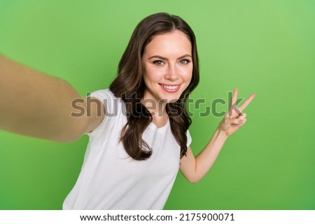 Photo of sweet dreamy woman dressed white t-shirt tacking selfie showing v-sign isolated green color background