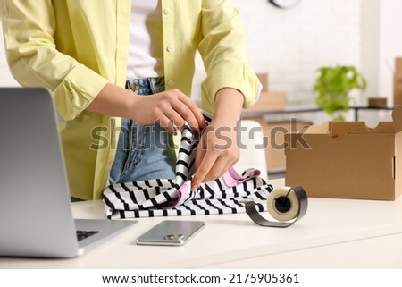 Seller packing clothes at workplace, closeup. Online store