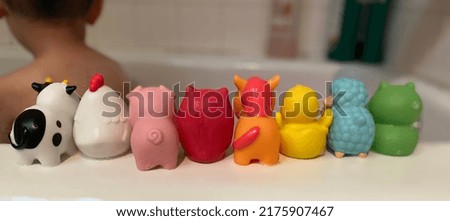 Farm animal bath toys lined up. Toddler in background having fun in the bathtub. Royalty-Free Stock Photo #2175907467