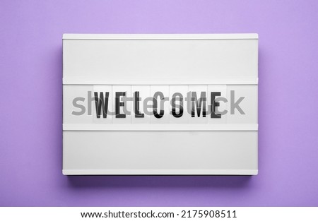 Lightbox with word Welcome on violet background, top view