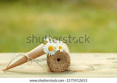 Bouquet of daisies and a coil of rope on a wooden floor in the garden.
