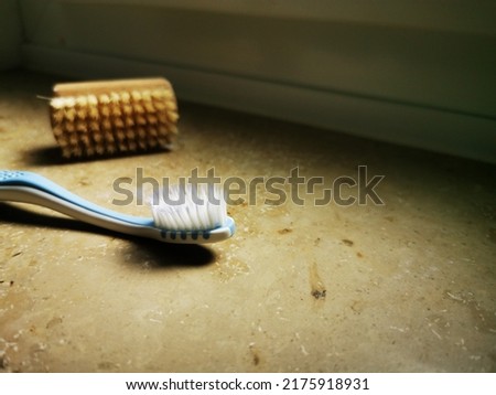 A toothbrush and a small bust for hands and fingernails in the bathroom. Royalty-Free Stock Photo #2175918931