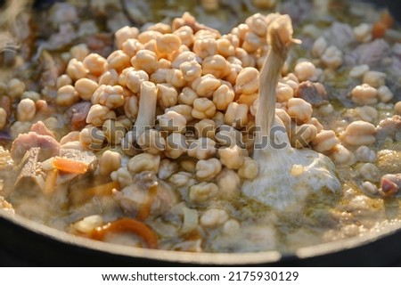Cast iron cauldron with pilaf on a fire. Garlic bulb and chickpeas. Shallow depth of field