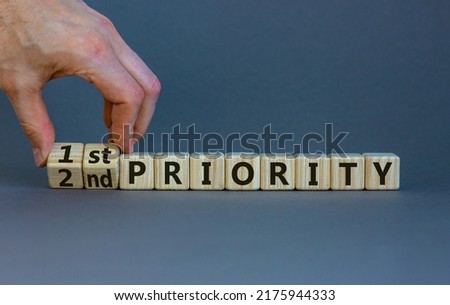 1st or 2nd priority symbol. Businessman turns wooden cubes and changes words 2nd priority to 1st priority. Beautiful grey background. Business, 1st first or 2nd second priority concept. Copy space. Royalty-Free Stock Photo #2175944333