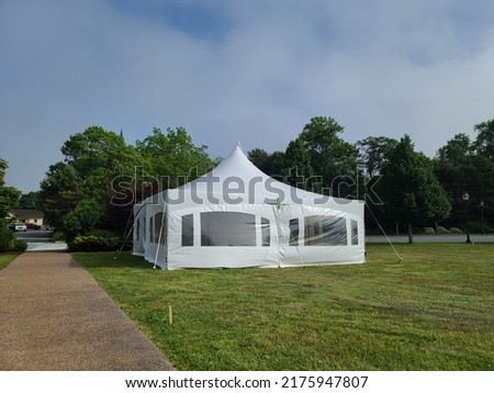 A large white tent being set up in the middle of a park area.