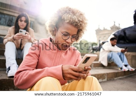 Group of people ignoring each other using phone with serious face. Latina woman focused on their mobile Royalty-Free Stock Photo #2175961047