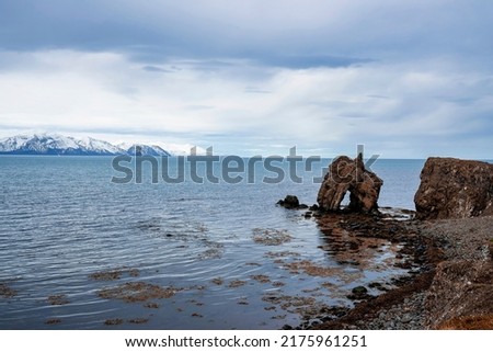 Scenic view of rock formations at seashore against sky. Idyllic view of snowcapped mountains in background. Beautiful scenery of Atlantic ocean in northern Alpine region.