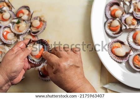 Top view of the hands of a cook presetning seafood on a ceramic plate in a restaurant