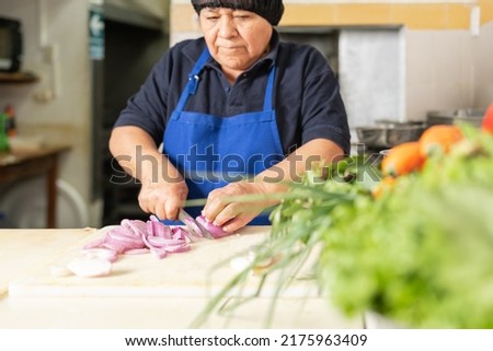 Focus on a female cook chopping onions in a restaurant