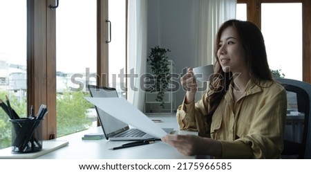 Beautiful young Asian businesswoman drinking a coffee working on laptop at office.
