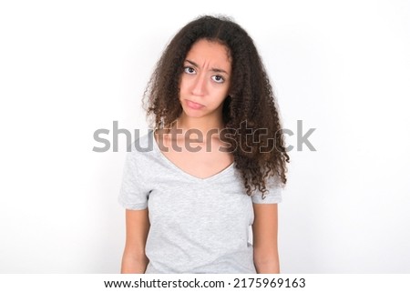 young beautiful brunette teen girl wearing grey t-shirt over white wall depressed and worry for distress, crying angry and afraid. Sad expression.