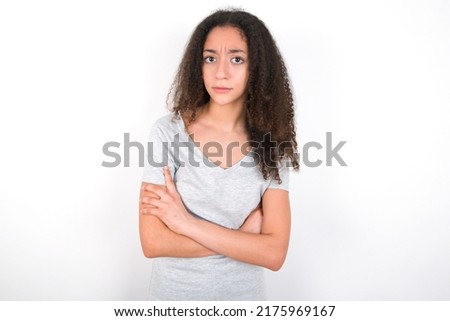 young beautiful brunette teen girl wearing grey t-shirt over white wall Pointing down with fingers showing advertisement, surprised face and open mouth