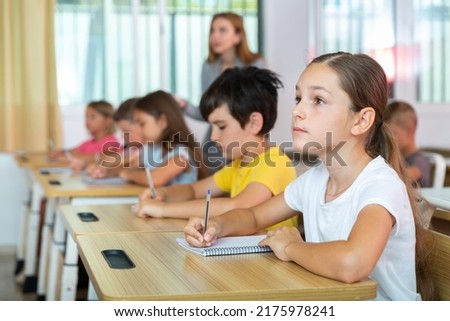 Schoolgirl sitting in classroom during lesson in elementary school. High quality photo Royalty-Free Stock Photo #2175978241