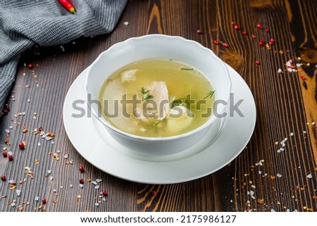 Chicken soup bouillon in a plate on wooden table
