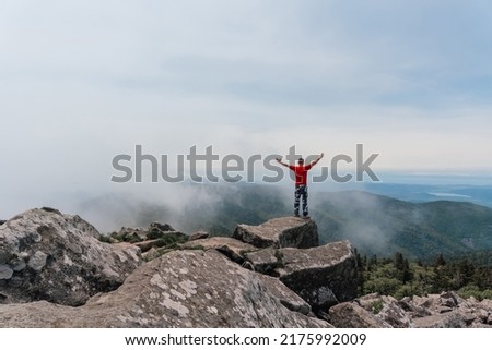 Hiker man on the top of the mountain enjoys the aerial view, raising his hands above the clouds. Mount Pidan. High quality photo