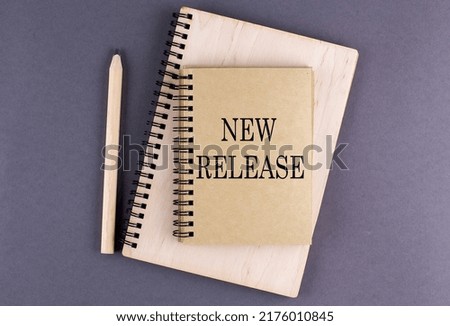 Word NEW RELEASE on a notebook with pencil on the grey background