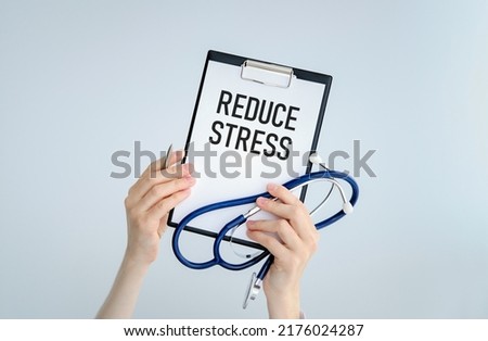 Clipboard with text REDUCE STRESS with doctor woman and stethoscope. Medical concept.