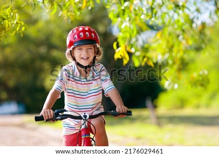 Child going to school on bike. Kids ride bicycle. Safe way to elementary school. Little boy with backpack on red bike wearing safety helmet. Healthy outdoor activity for young student. Royalty-Free Stock Photo #2176029461