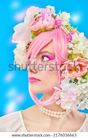 Beauty girl. Portrait of a beautiful girl with bright pink makeup and pink hair with floral wreath on her head. Japanese anime style. Spring and summer beauty. Blue background with lights.