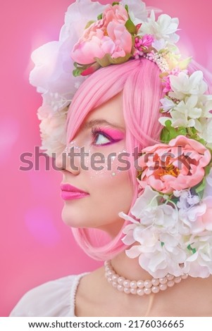 Spring and summer beauty. A lovely smiling girl with bright pink makeup and pink hair with floral wreath on her head posing in profile. Japanese anime style. Pink background. Beauty girl. 