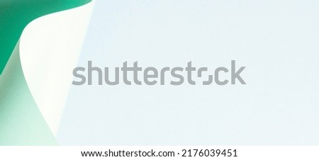 Abstract wave of pastel green paper on light blue background. Creative geometric curved paper with light and shadows. Abstract geometry background with copy space