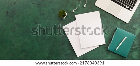 Blank magazines, laptop and notebook on green background with space for text