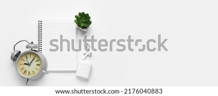 Notebook, earphones and alarm clock on white background with space for text