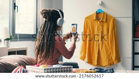 Woman taking picture of her used clothes, she is selling her clothing online