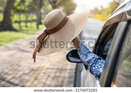 Happy enjoy and freedom in traveling trip with raised hand and holding beautiful hat outside of window car in summer vacation holiday