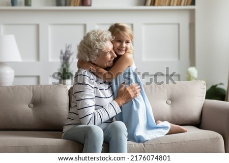 You are the best granny in world. Adorable little preschool girl holding arms around neck of mature retired grandmother, happy grandma is excited to meet small granddaughter hugging her in living room Royalty-Free Stock Photo #2176074801