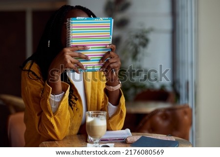 A clever african girl sits in a coffee shop and looking at the textbook.