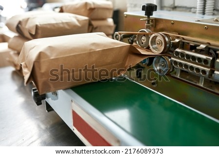 Close up of pack machine with paper package of coffee beans at table on factory. Coffee process making and production. Small business. Modern automated manufacturing equipment. Nobody Royalty-Free Stock Photo #2176089373