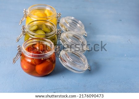 Homemade Pickles Canned Food Cucumbers Cherry Tomatoes and Small Yellow Squash on Blue Background Copy Space