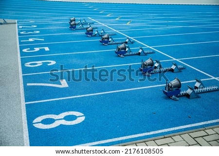 Running background. Start line with big numbers, athletics track and starting blocks. Blue colors Royalty-Free Stock Photo #2176108505