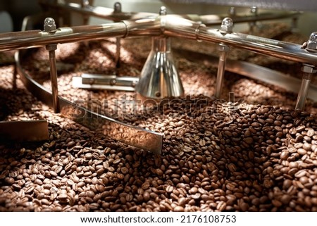 Natural roasted coffee beans mixing in mixer of industrial roasting machine on factory. Coffee process making and production on export. Small business. Modern automated manufacturing equipment Royalty-Free Stock Photo #2176108753