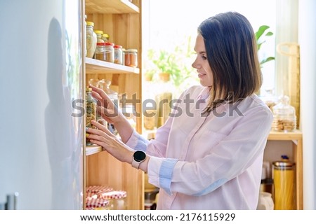 Young woman in kitchen with containers jars of food