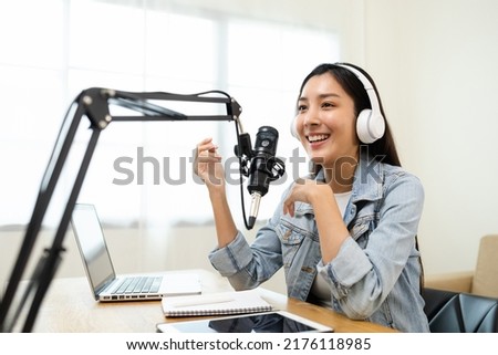 Content creator woman host streaming her a podcast on laptop with headphones and microphone interview cheering guest conversation at broadcast studio. Blogger motivation recording voice over radio. Royalty-Free Stock Photo #2176118985