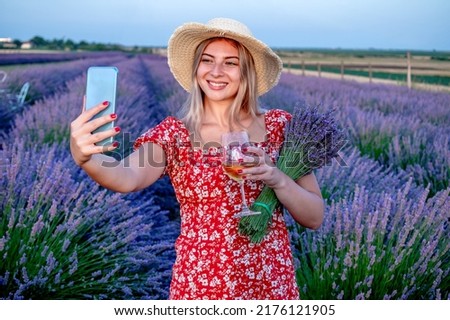 Beautiful blonde woman taking selfie pictures outdoors in a picturesque lavender field.