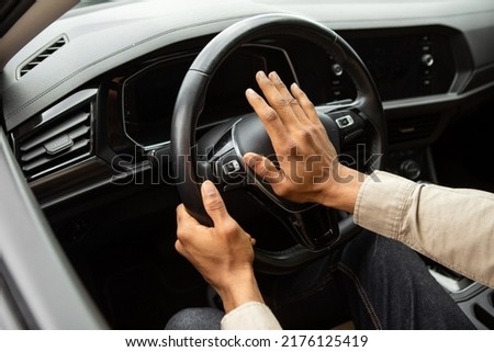 Man driving a car with hand on horn button Royalty-Free Stock Photo #2176125419